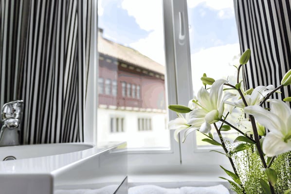 Un baño con lavamanos blanco, un espejo y una ventana con cortinas.