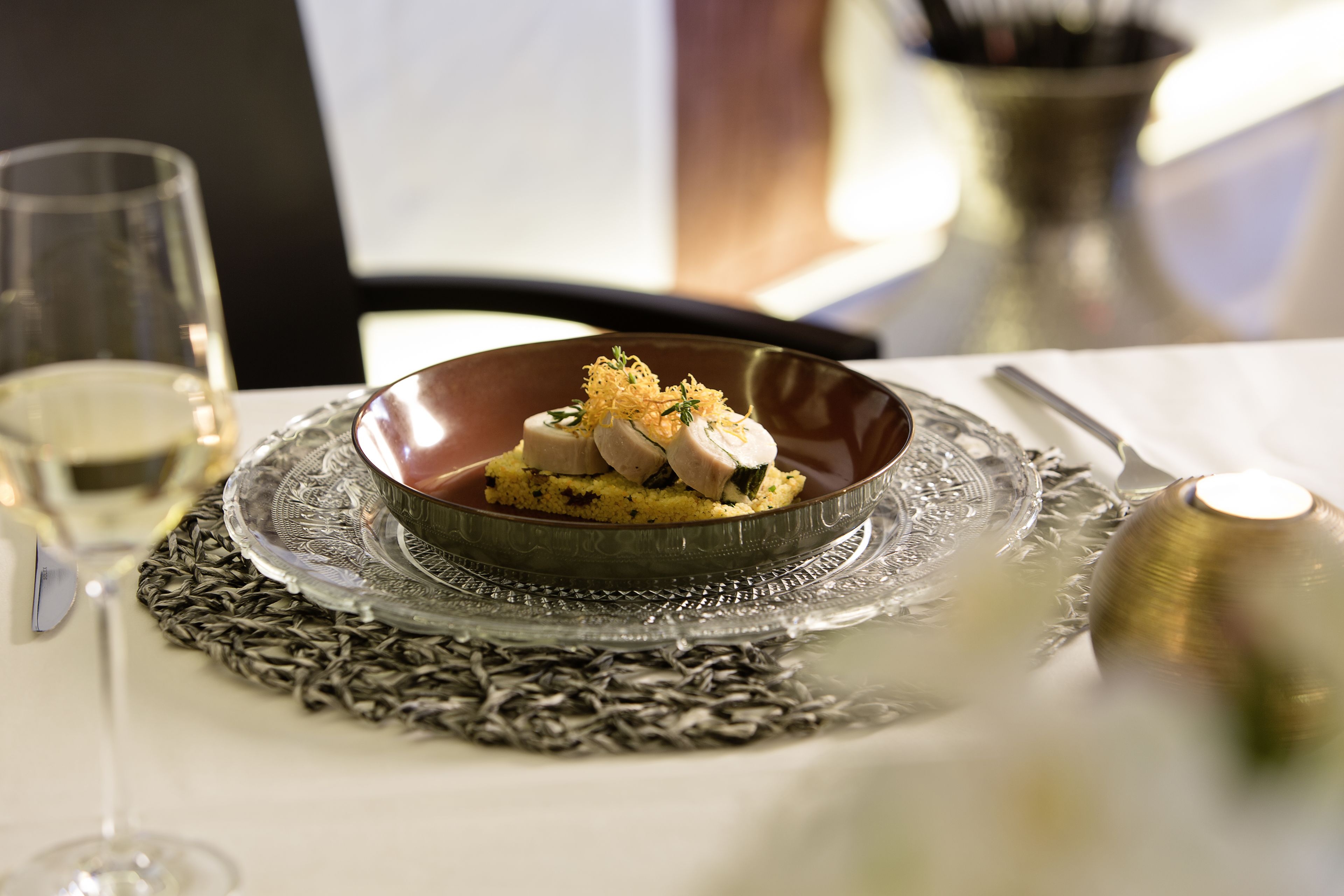 Un plat décoratif, présenté dans un bol ornemental, est posé sur une table recouverte d’un set de table en fibres tressées.