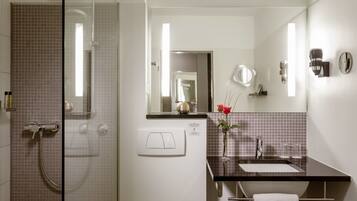 A bathroom with a glass shower enclosure, a sink with a mirror, and a towel rack.