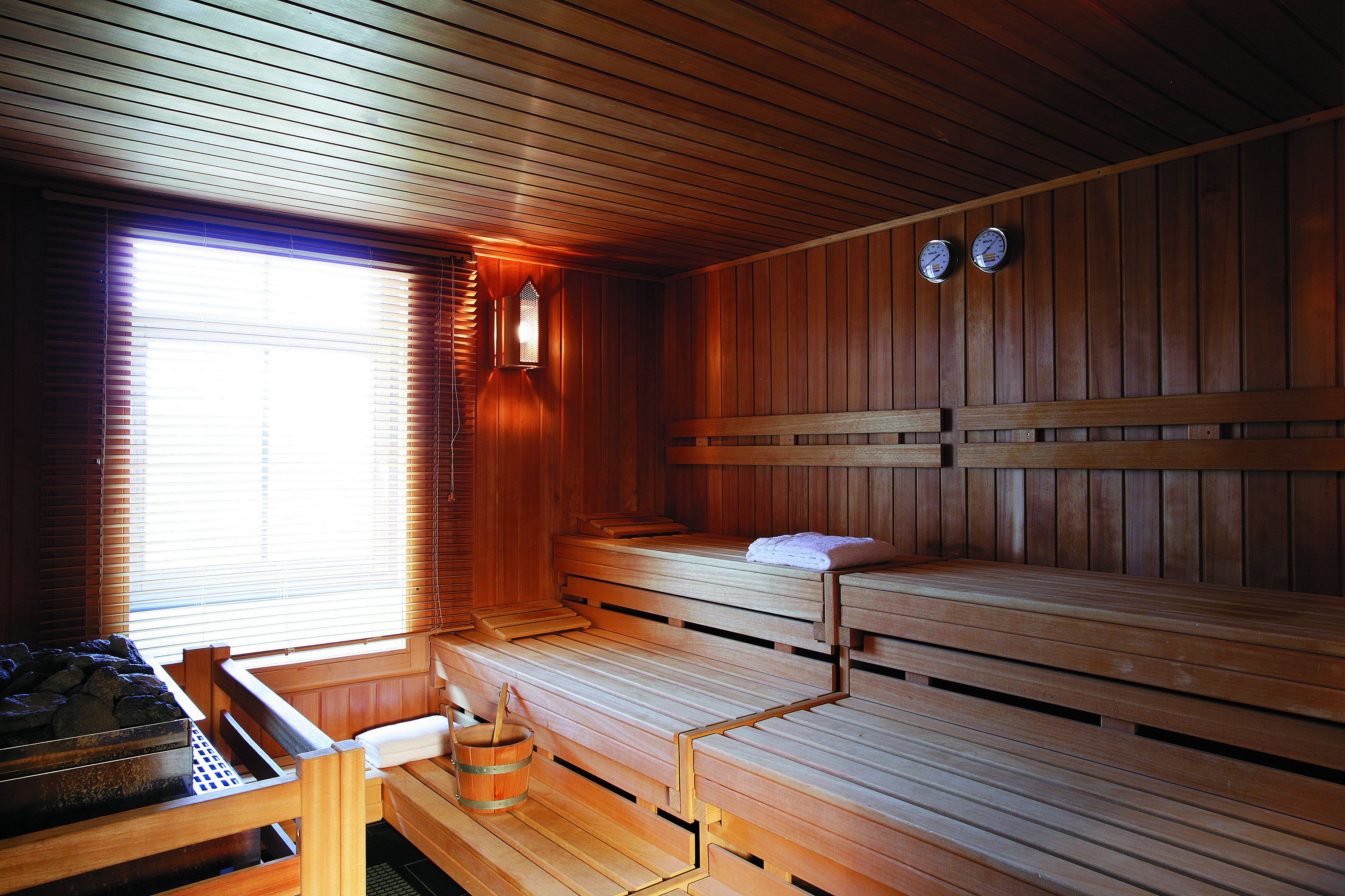 A sauna with wooden benches and a bench seat, a wooden bench with a towel, and a wooden bench with a towel.