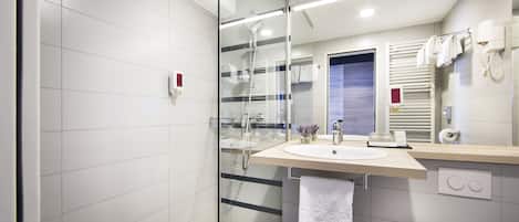 A modern bathroom with a glass shower enclosure, a sink with a towel hanging on the wall, and a toilet.