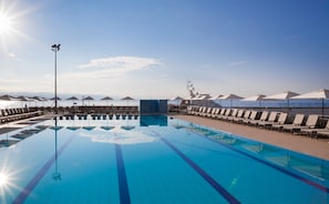 A large, clear swimming pool with sun reflecting on the water, surrounded by lounge chairs and umbrellas, with a view of the sea and a yacht in the background. - Hotel Admiral - Liburnia (Opatija)
