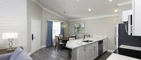A modern kitchen with white cabinetry, a black refrigerator, and a dining area with a table and chairs.