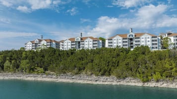 A multi-story hotel with balconies, located on a rocky shoreline with a view of the sea.