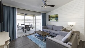 A modern living room with a sofa, coffee table, and a ceiling fan. There is a glass door leading to an outdoor area with a view. - Westgate Branson Lakes Resort (Hollister)