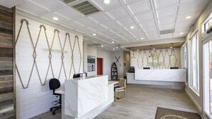 A reception area with a white reception desk, wooden paneling, and a large window. - Westgate Branson Lakes Resort (Hollister)