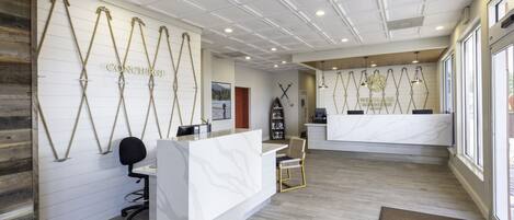 A reception area with a white reception desk, wooden paneling, and a large window.