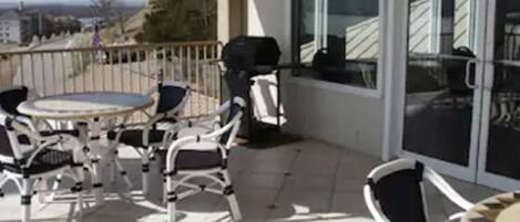 Un balcón con mobiliario exterior, una mesa y una parrilla.