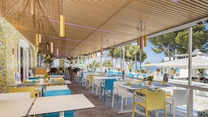 A restaurant with outdoor seating, a tiled wall, and hanging lights.