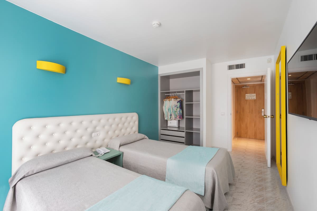 A bedroom with two beds, a wardrobe, and a bathroom.