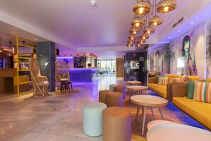 A modern hotel lobby with seating areas, a reception desk, and a large mural. - Sotavento Club Apartments - Only Adults (Calvia)