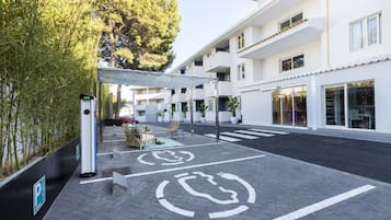 A modern building with a covered outdoor seating area, a bicycle parking symbol, and a pedestrian crossing.