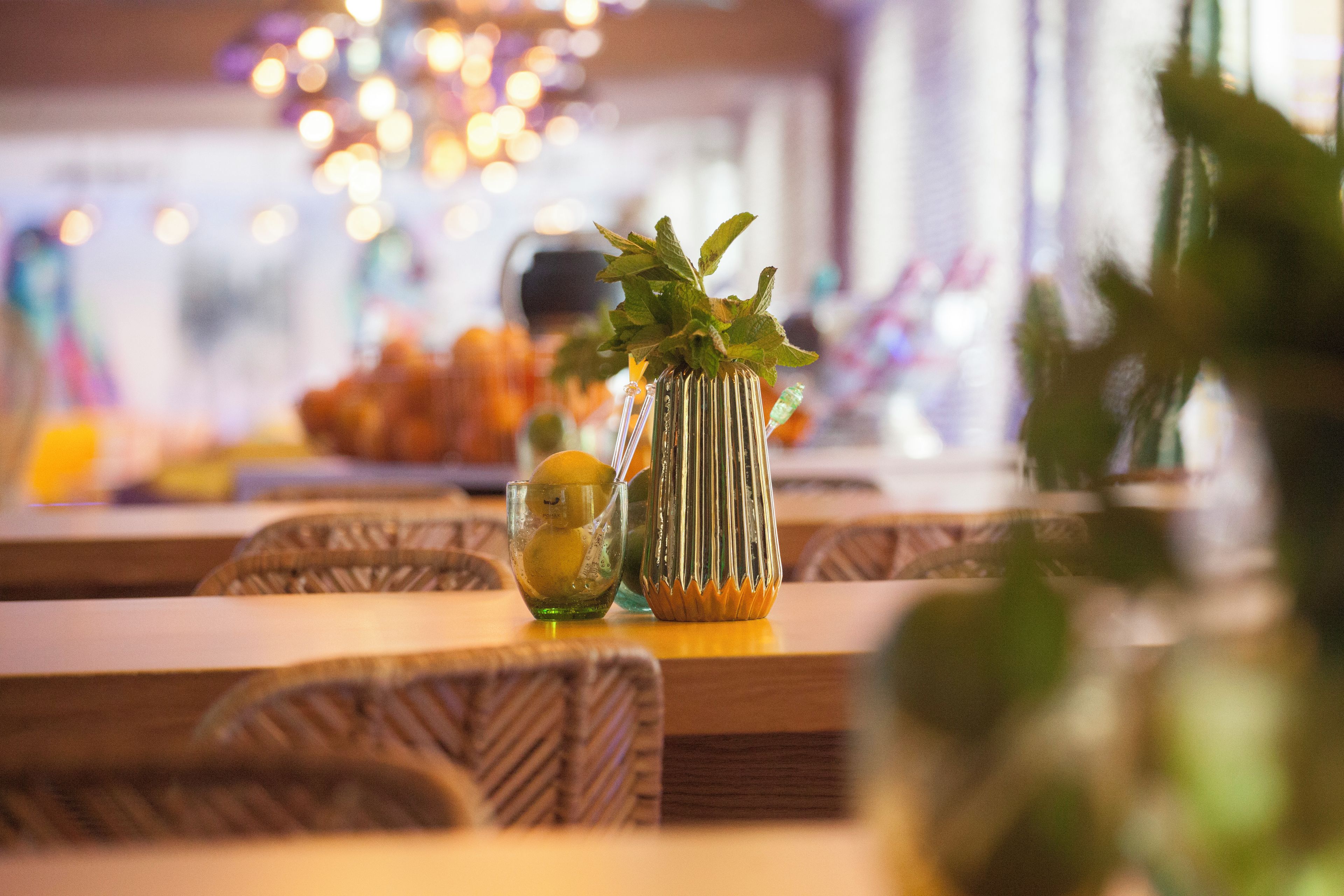 A dining table with a glass of water, a vase with a plant, and a plate of food.