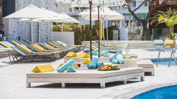 A poolside area with lounge chairs, umbrellas, and a swimming pool.
