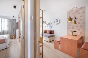 A modern hotel room with a wooden floor, a bed with a grey mattress, a small wooden table, and a seating area with a bench. - Sotavento Club Apartments - Only Adults (Calvia)