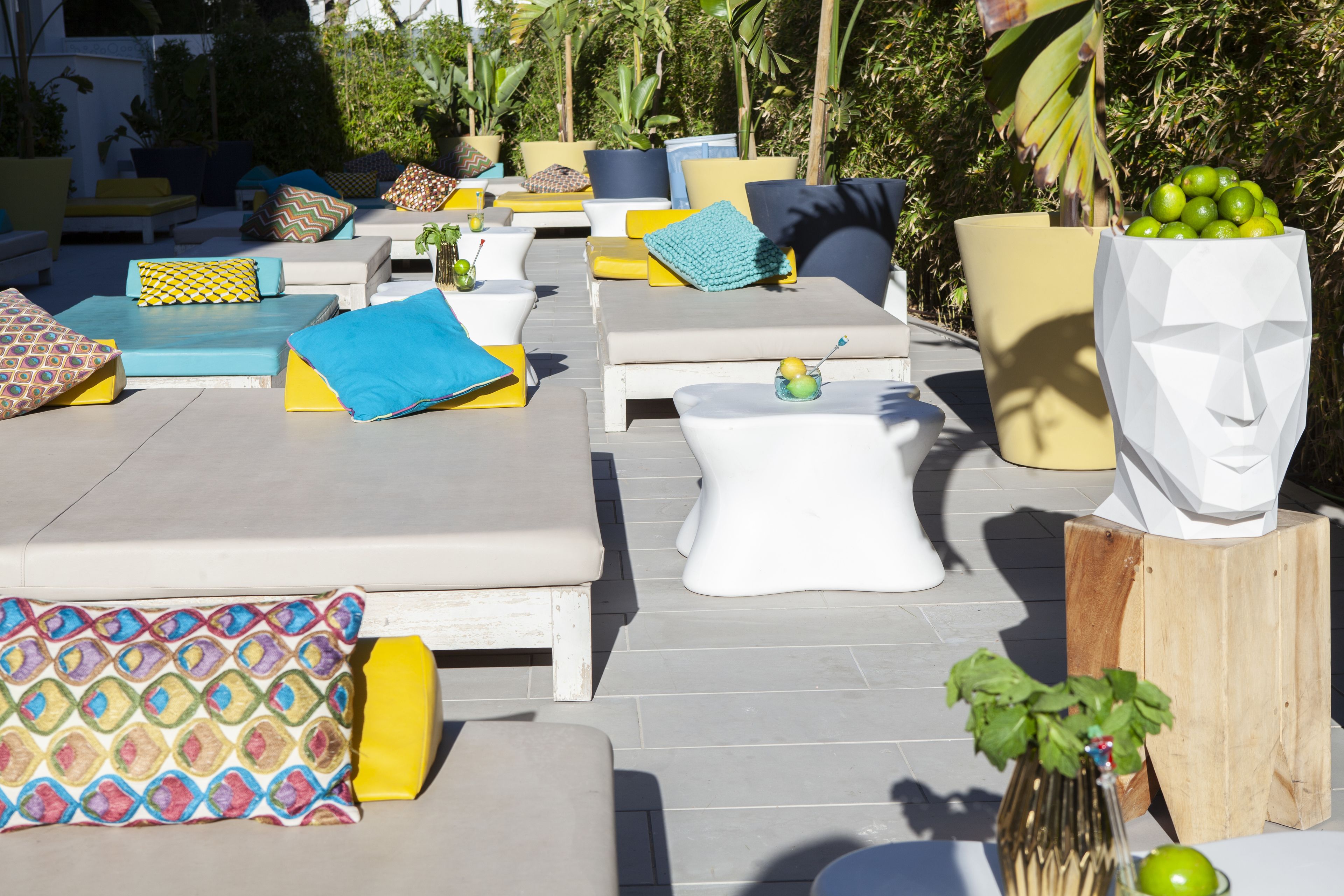 An outdoor lounge area with multiple seating options, including sofas and chairs, arranged on a tiled patio.