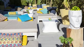 An outdoor lounge area with multiple seating options, including sofas and chairs, arranged on a tiled patio.