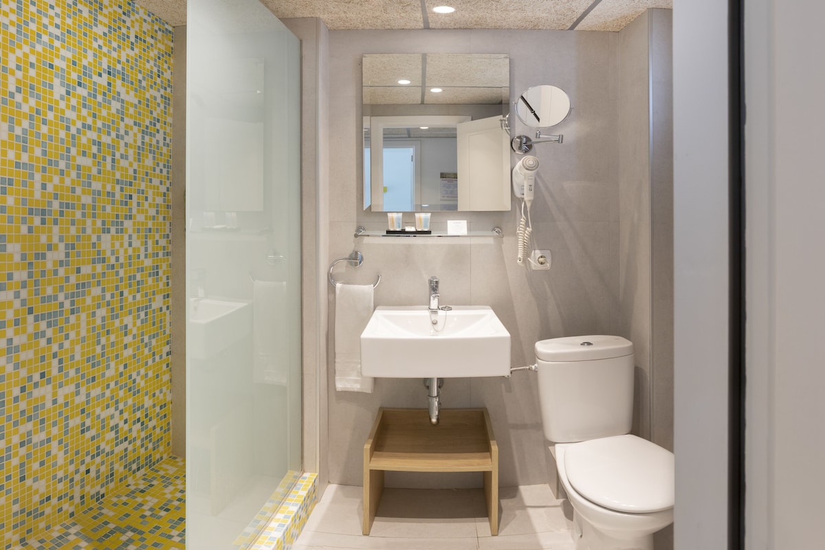 Un baño con pared de mosaicos, un lavabo, un inodoro y un espejo.