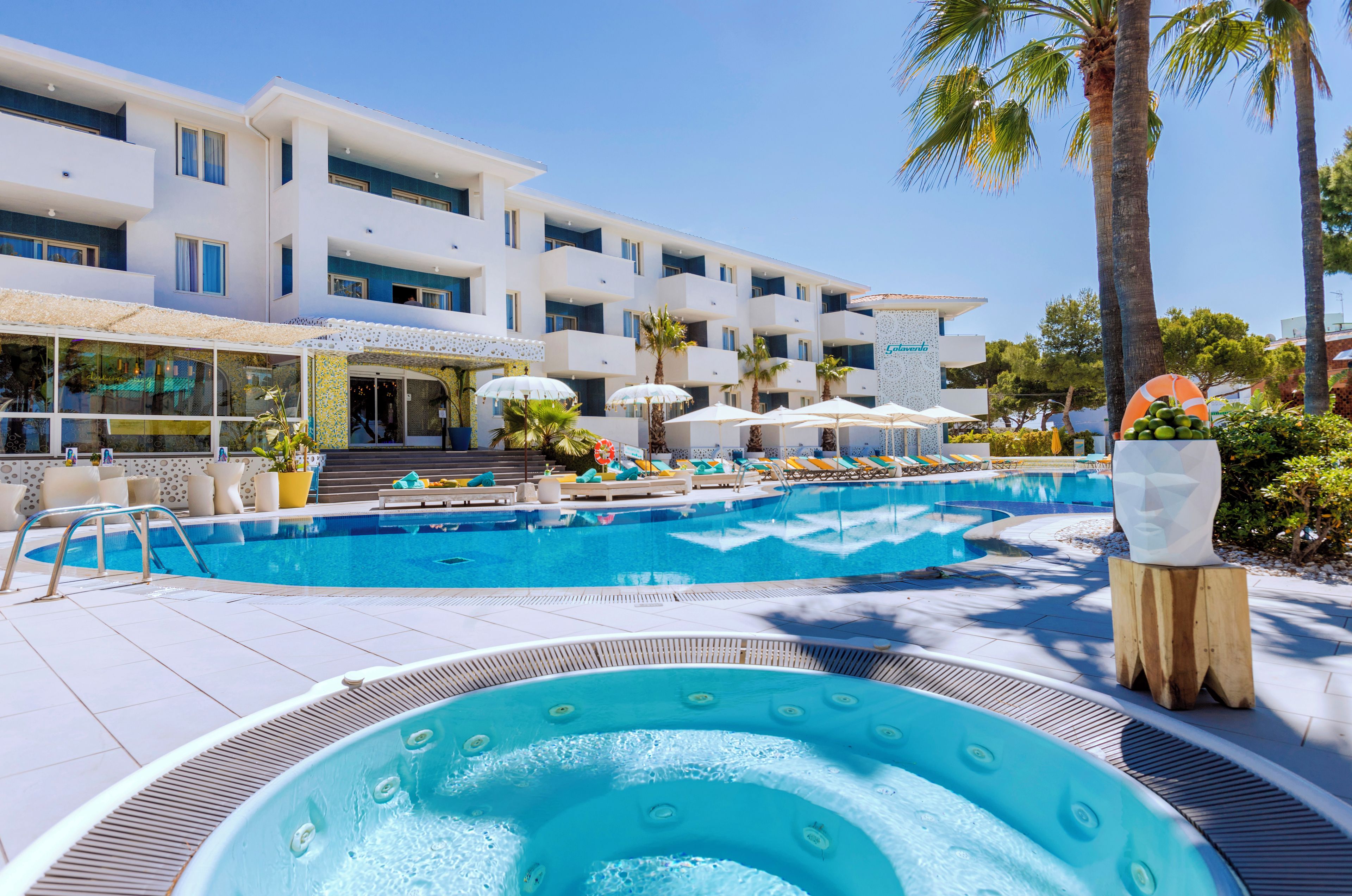 A hotel with a swimming pool, lounge chairs, and a hot tub.