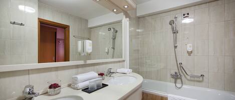 A modern bathroom with two sinks, a large mirror, a shower with a handheld showerhead, and a bathtub.