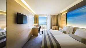 Ein Hotelzimmer mit einem großen Bett, einem Schreibtisch, einem Flachbildfernseher und Blick auf den Ozean.
