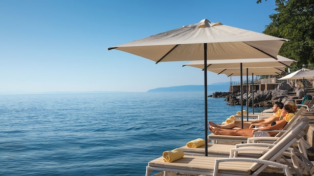 Ein Seebad mit Liegestühlen und Sonnenschirmen am Wasser.