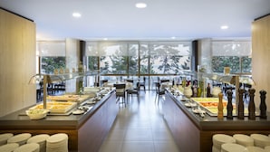 Ein reichhaltiges Buffet mit verschiedenen Speisen und Beilagen, präsentiert auf einer Theke. Im Hintergrund sind Stühle und Tische zu sehen.