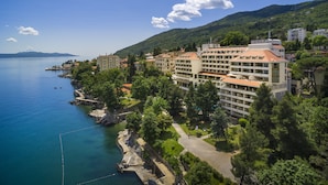 Ein Hotel an der Küste mit mehreren Stockwerken, einem Jachthafen und üppiger Bepflanzung.