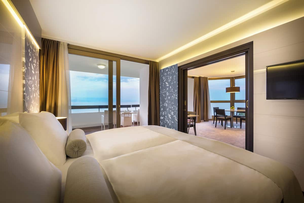 A hotel room with a large bed, a desk, and a view of the ocean.