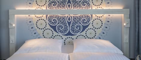 A bed with a white headboard and a decorative wall pattern.