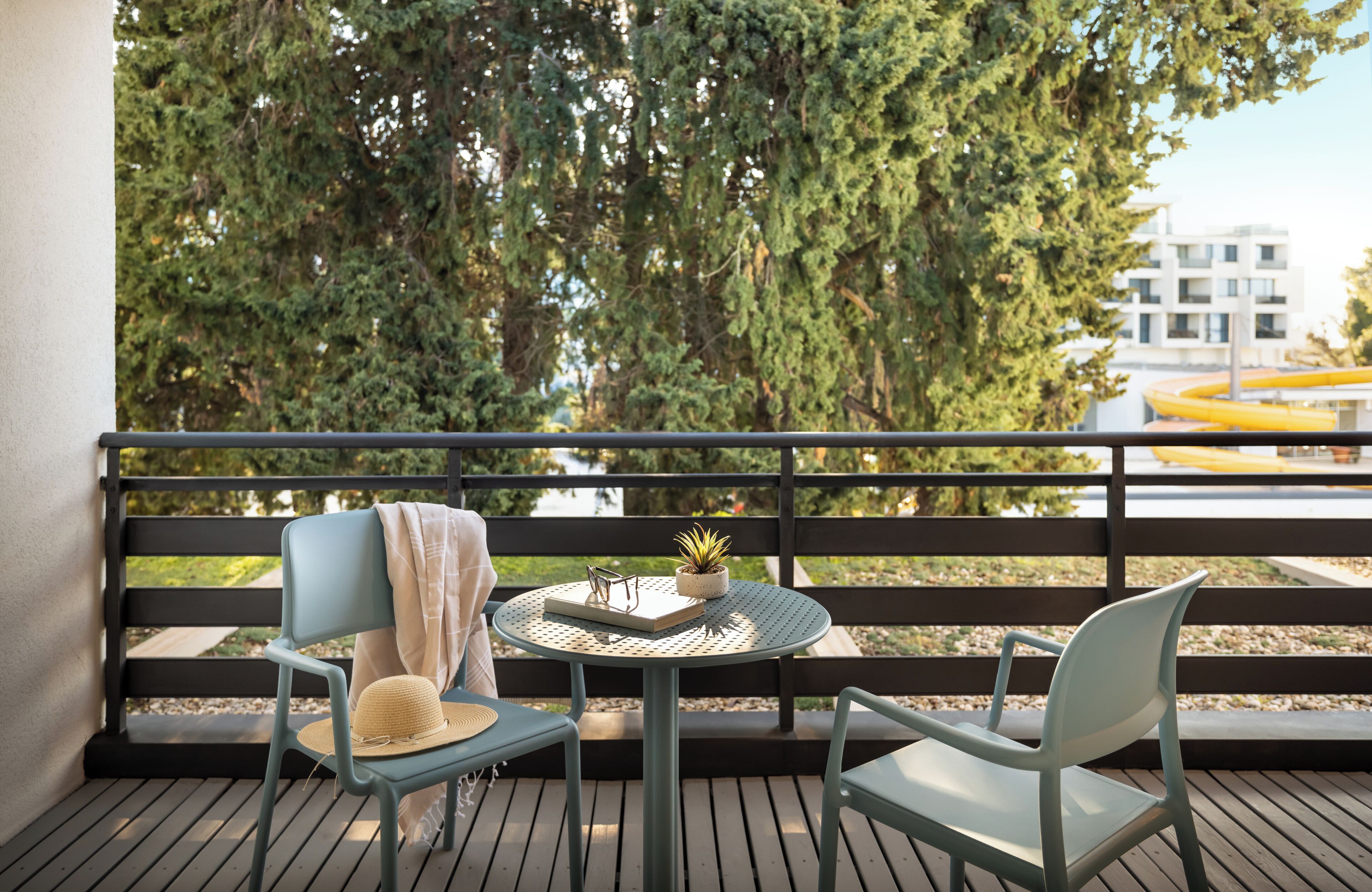 Ein Balkon mit zwei Stühlen, einem kleinen runden Tisch und einem Blumentopf.