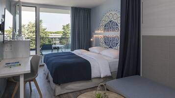 A modern hotel room with a bed, a desk, and a view of the outdoors.
