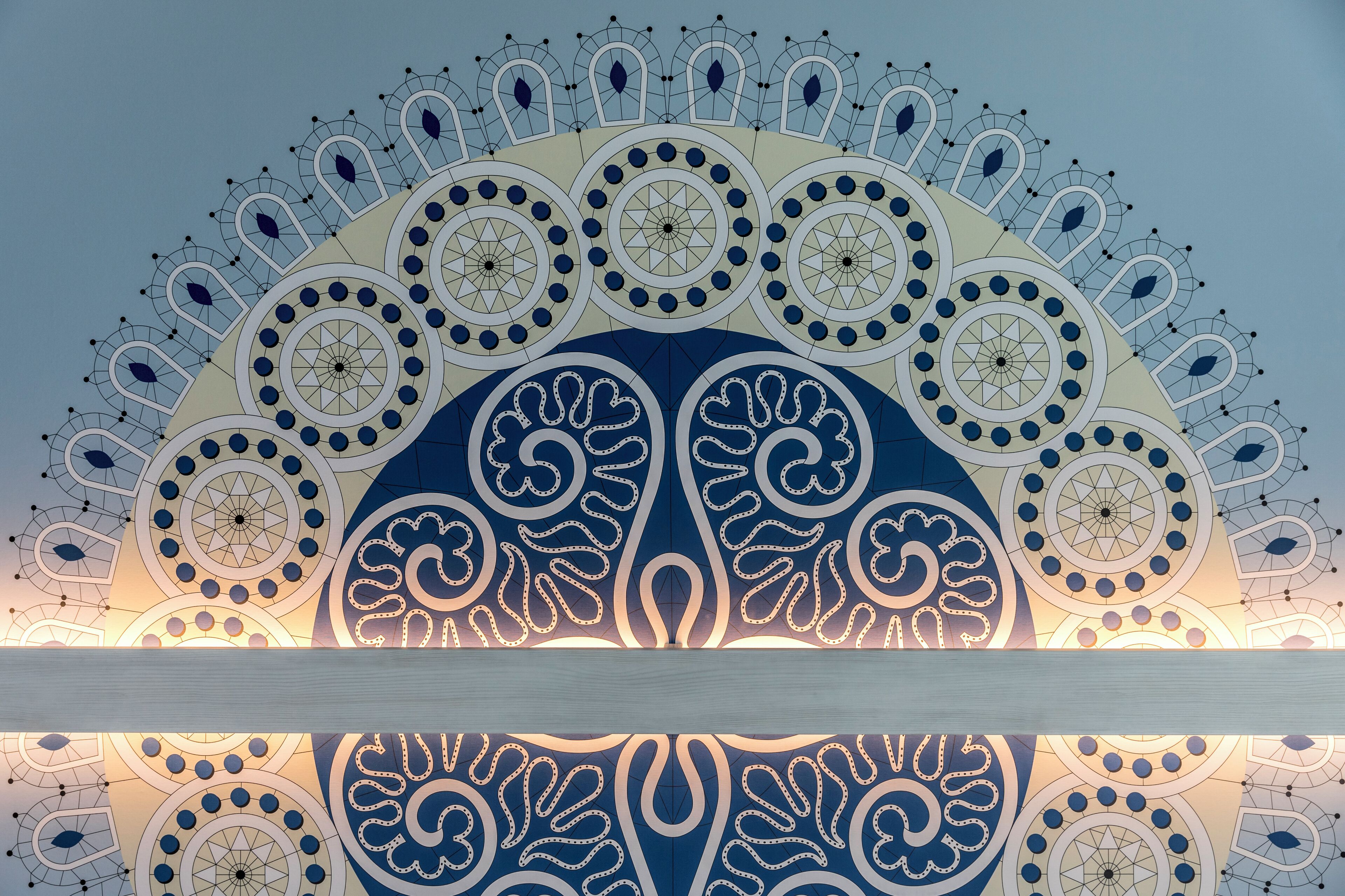 A ceiling with intricate geometric and floral patterns, likely part of a building's interior design.