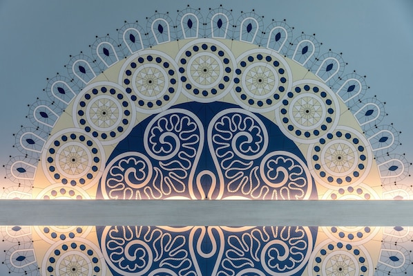 A ceiling with intricate geometric and floral patterns, likely part of a building's interior design.