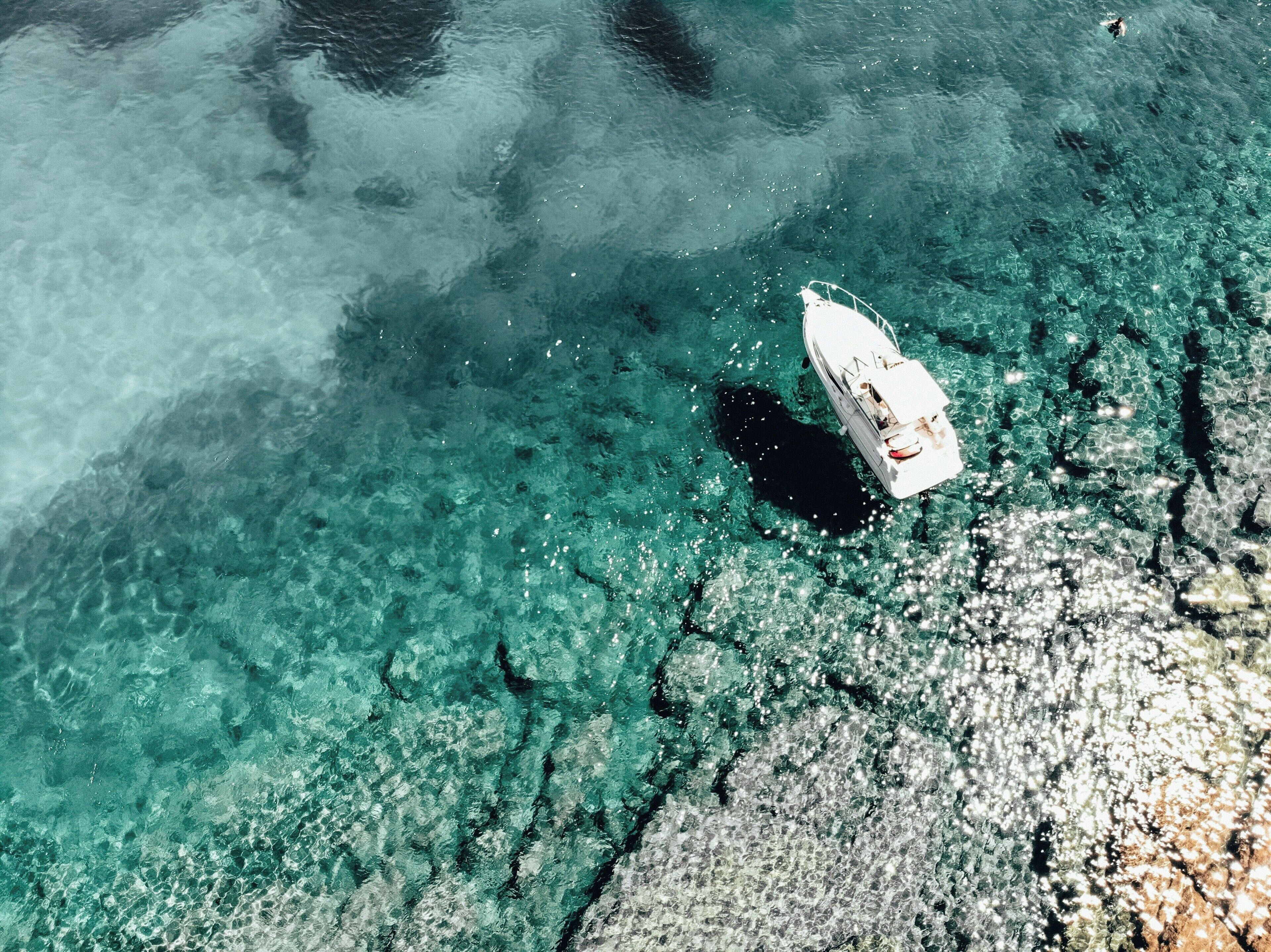 Un bateau sur une eau turquoise et limpide, près d’une côte rocheuse.