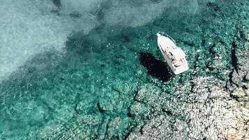 A boat on clear turquoise water near a rocky shoreline.