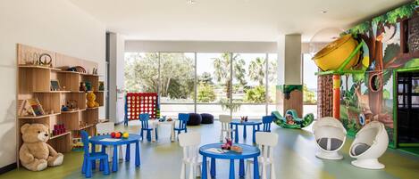 Een kinderspeelruimte met tafels, stoelen en educatief speelgoed.