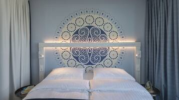 A neatly made bed with a decorative headboard, a bedside table with a book, and a nightstand with a lamp.