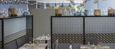 Un intérieur de restaurant moderne, avec des cloisons à motifs, des meubles noirs et blancs et des luminaires suspendus.