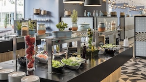 Una cocina moderna con un montaje tipo bufé, que incluye vitrinas de vidrio, diferentes opciones de comida y plantas decorativas.