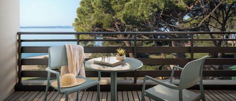 A balcony with two chairs, a small round table, and a potted plant.