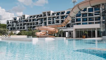 Experience the unique architecture and tranquil surroundings of this hotel, featuring a pool with a clear blue water surface and lush greenery.