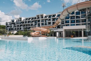 Una piscina techada, una piscina al aire libre, sombrillas