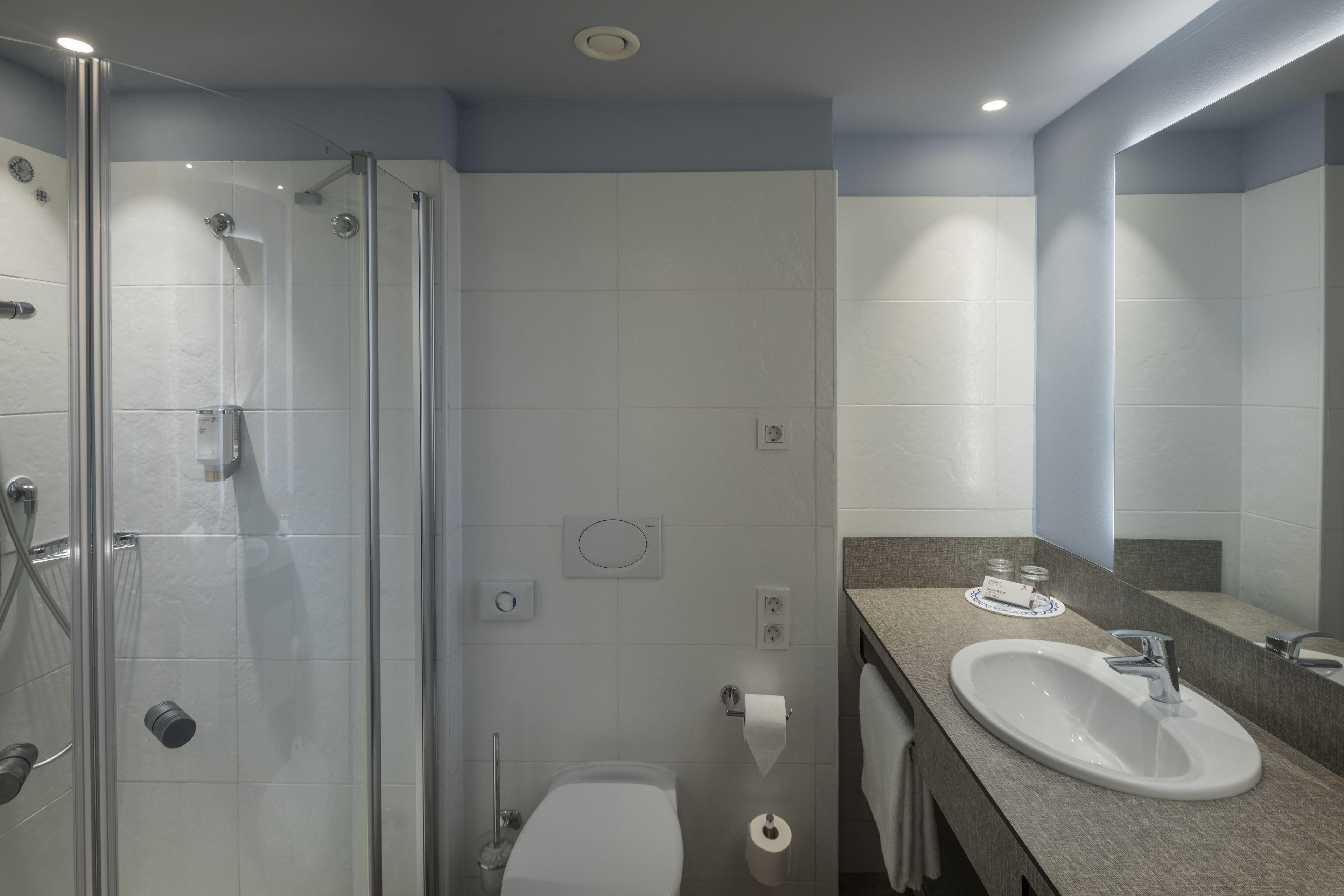 A modern bathroom with a glass shower enclosure, a sink with a mirror, and a toilet.