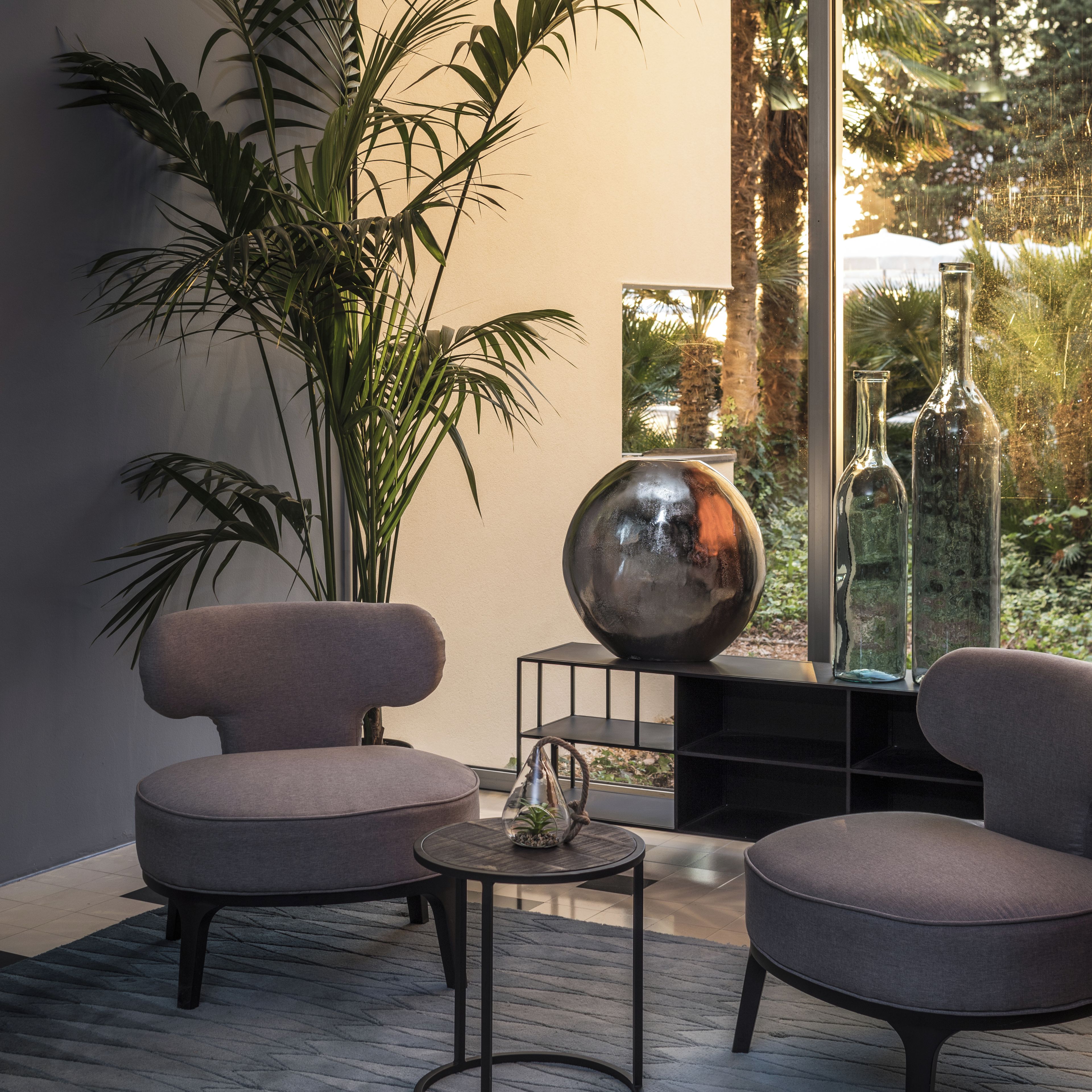 Un interior moderno con dos sillones, una mesita redonda, una planta en maceta y una esfera decorativa grande.