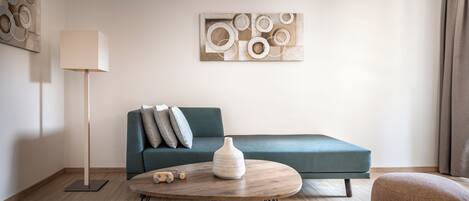 A modern living room with a teal sofa, a wooden coffee table, and a lamp.
