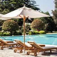 Un espace aménagé au bord de la piscine, avec des chaises longues et un parasol.