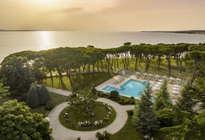 A resort with a swimming pool, lounge chairs, and a view of the sea. - Falkensteiner Hotel Adriana l Adults Only (Zadar)