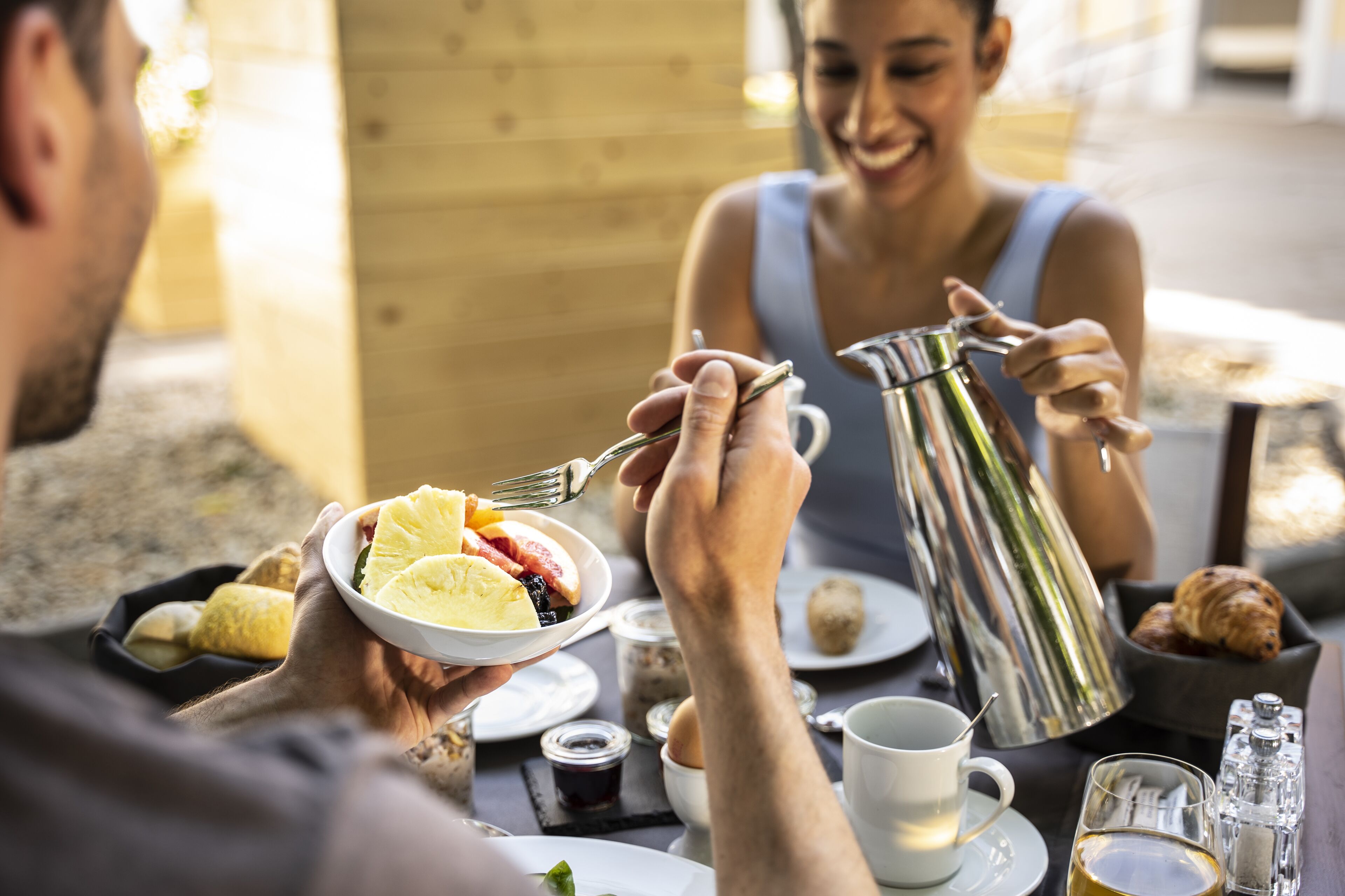 Une table mise pour le petit-déjeuner, avec une cafetière, des assiettes remplies de nourriture et une tasse.