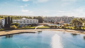 A hotel with a pool, multiple buildings, and surrounding greenery.